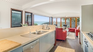 Cozinha moderna com uma ilha grande, máquina de lavar louça embutida e vista para o oceano.