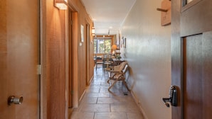 Un couloir aux murs et aux portes en bois, qui mène à une salle à manger avec des chaises et une table.