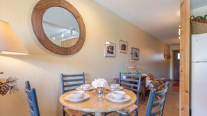 Un coin repas avec une table ronde dressée pour quatre personnes, entourée de chaises bleues.