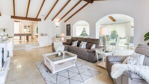 Un vaste salon doté d’un haut plafond, comprenant un ensemble de canapés, une table basse et un coin repas à l’arrière-plan.