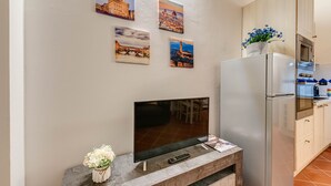 A modern kitchen with a built-in TV, a refrigerator, and a microwave. - Boboli Guest House Centro Storico Fiorentino (Firenze)
