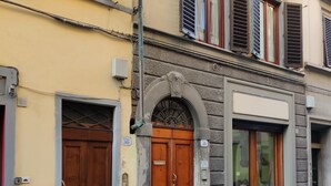 A building with a large wooden double door, a stone archway, and a window with a view of a person inside. - Boboli Guest House Centro Storico Fiorentino (Firenze)