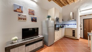 A modern kitchen with a flat-screen TV, a refrigerator, and a microwave. There are cabinets and a tiled backsplash. - Boboli Guest House Centro Storico Fiorentino (Firenze)
