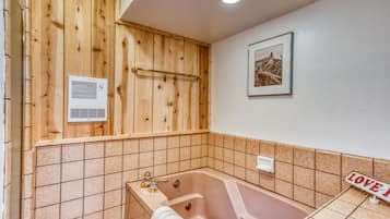 A bathroom with a wooden panel wall, a bathtub, a towel rack, a framed picture, and a 'LOVE' sign.