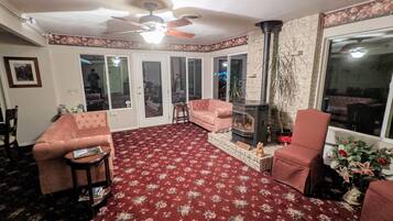 Uma sala de estar aconchegante com lareira, ventilador de teto e uma grande janela.