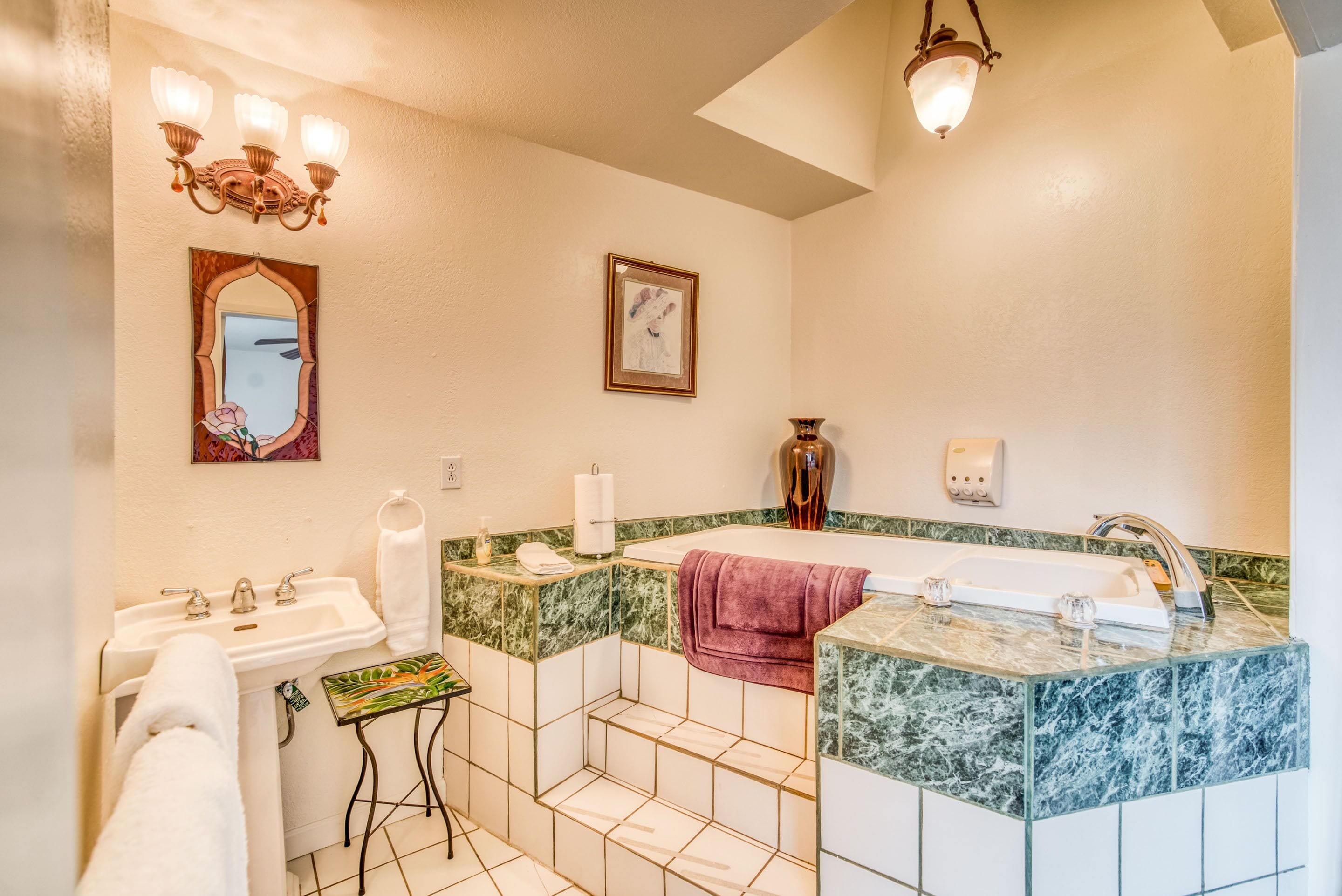 A bathroom with a sink, mirror, vanity, and bathtub.