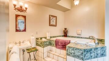 A bathroom with a sink, mirror, vanity, and bathtub.