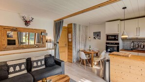 A cozy living room with a sofa, a dining area with a table and chairs, and a kitchen with modern appliances. - Apartment Cry - Alpes Agency - Central Chamonix - Sleeps 2-4 (Chamonix-Mont-Blanc)