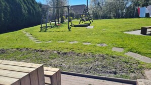 A grassy outdoor area with a wooden swing set and a picnic table. - Ferienwohnung 9 & 40 (Stedesdorf)