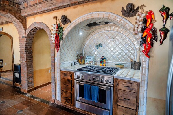 A kitchen with a tiled backsplash, a stove, oven, and wooden cabinets.