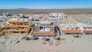 An aerial view of a resort with multiple buildings, including a large resort building with a pool and a smaller building with a red roof. - La Rosa del Encanto Beachfront Ground Floor West (Playa Encanto)
