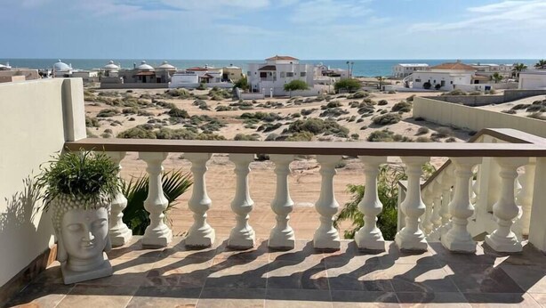 Un balcón con vistas a la playa y edificios.