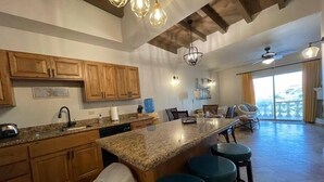 Una cocina amplia con armarios de madera, encimera de granito y una isla grande con taburetes.