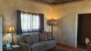 A living room with a sofa, a lamp, and a window with curtains.
