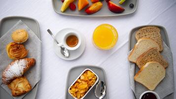 A breakfast setting with croissants, fruit, toast, and beverages on a table.