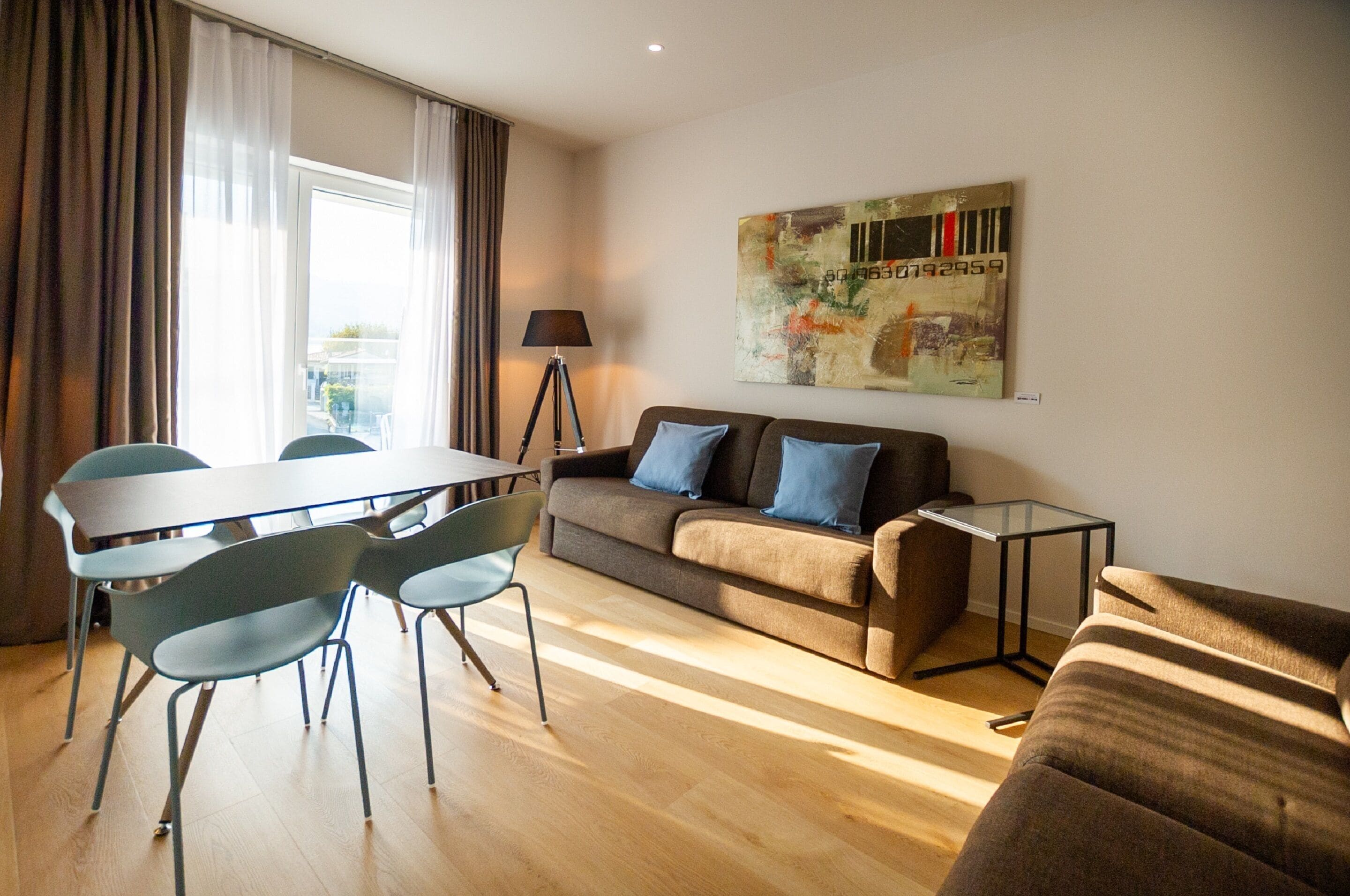 Una sala moderna con un sofá, una mesa de comedor con sillas y una lámpara.