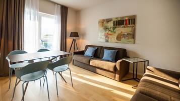 Una sala moderna con un sofá, una mesa de comedor con sillas y una lámpara.