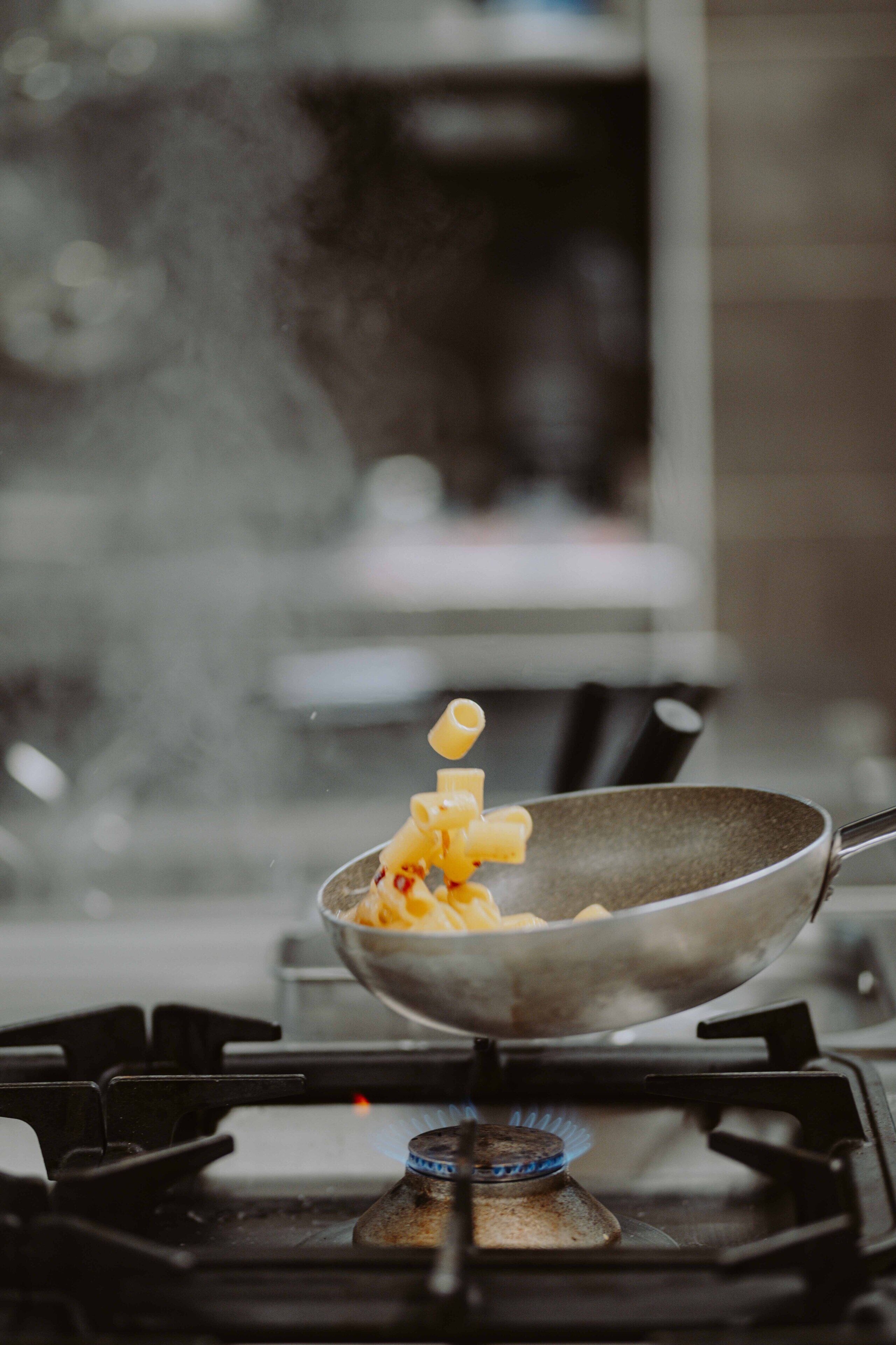 Une cuisine avec une cuisinière à gaz et une poêle qui y est posée.