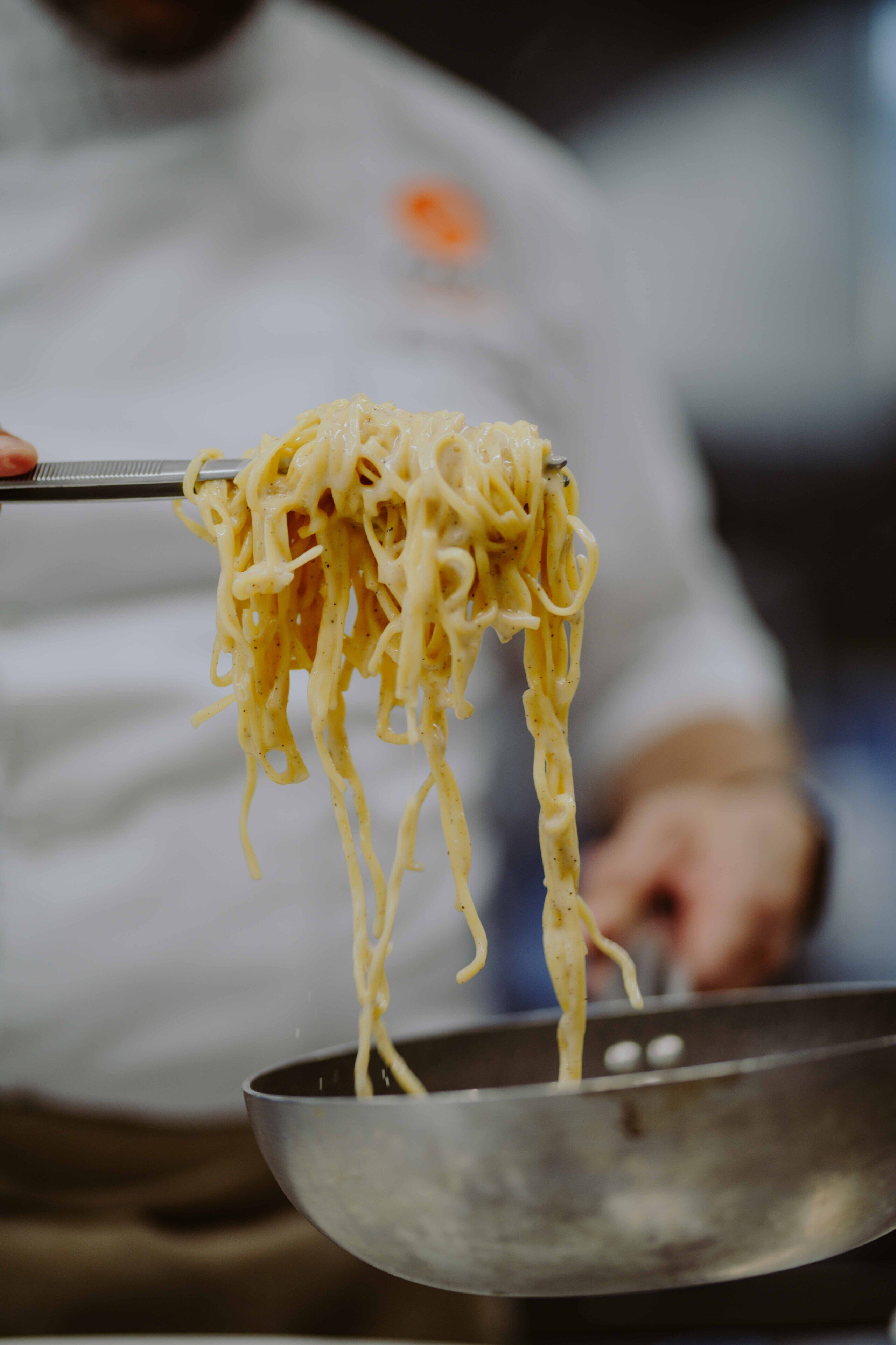 Eine Person hält eine Schüssel Spaghetti mit einer Gabel.