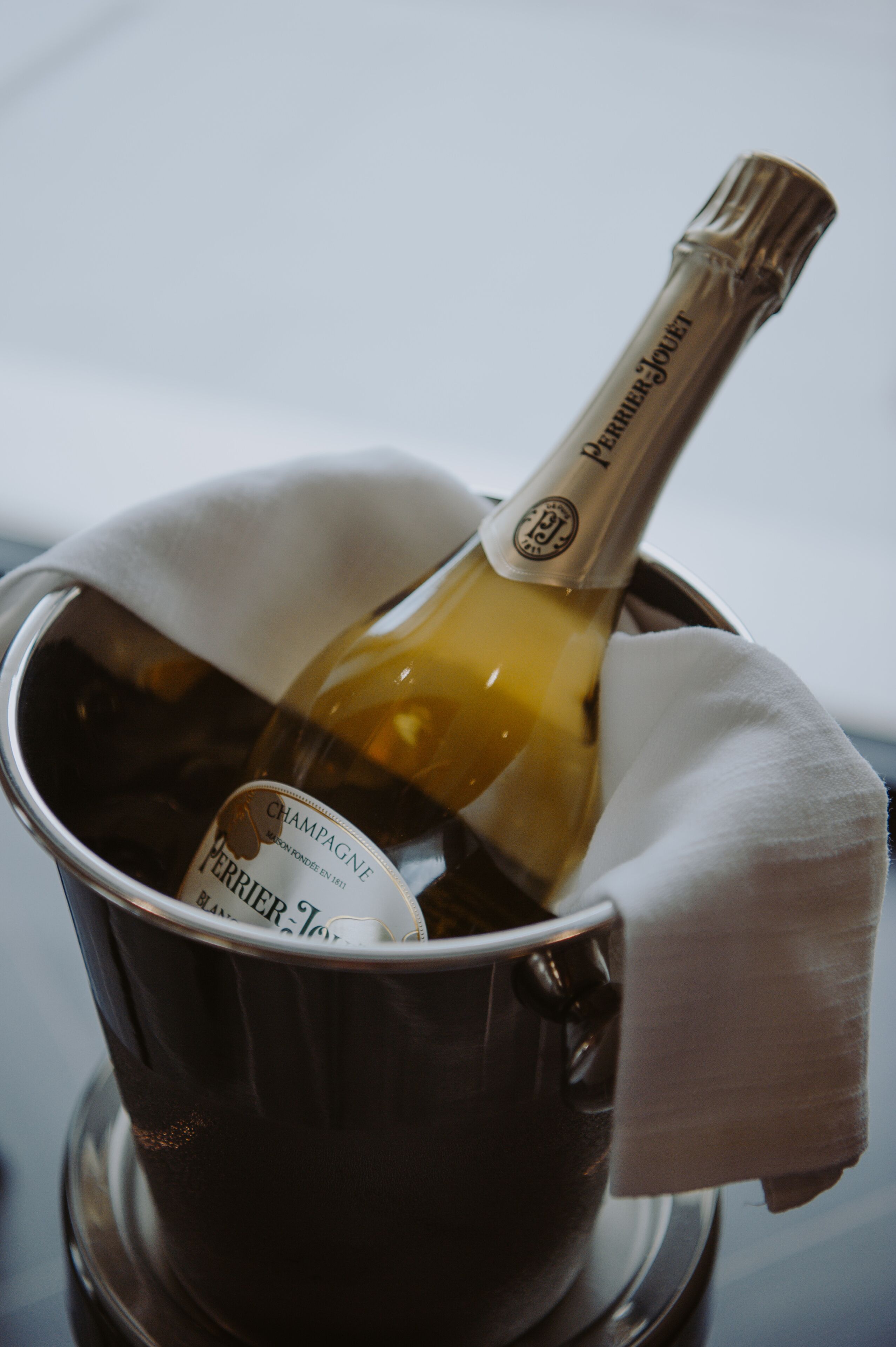 Eine Flasche Perrier-Jouët Champagner in einem Metallkübel mit weißer Serviette.