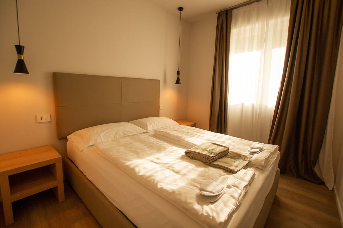 A neatly made bed with a headboard, a bedside table, and a lamp.