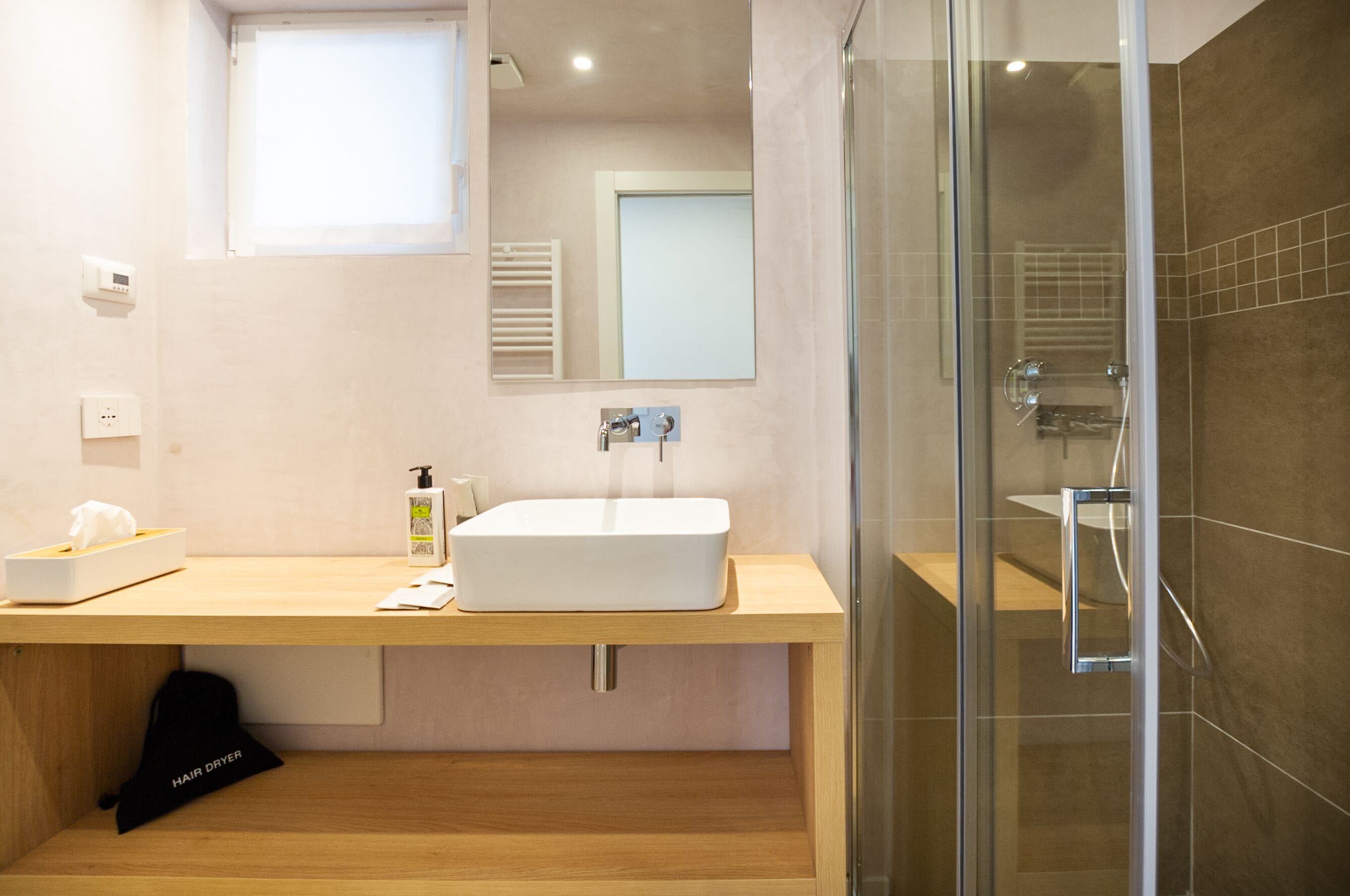 A modern bathroom with a large white sink, a glass shower enclosure, and a wooden vanity.