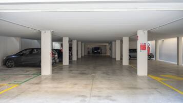 A multi-level parking garage with several cars parked, concrete pillars, and clear floor markings.