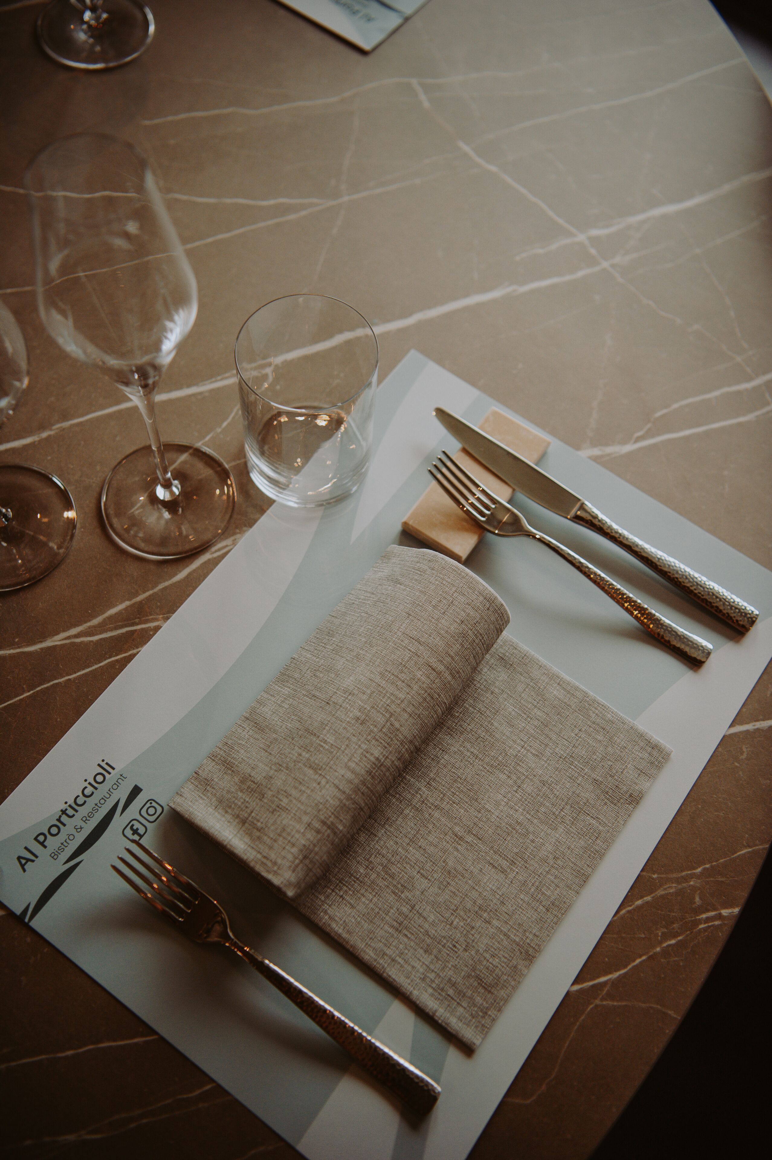 A table set with a folded napkin, a fork, a knife, and a glass.