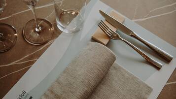 Una mesa dispuesta con un servilleta doblada, un tenedor, un cuchillo y una copa.