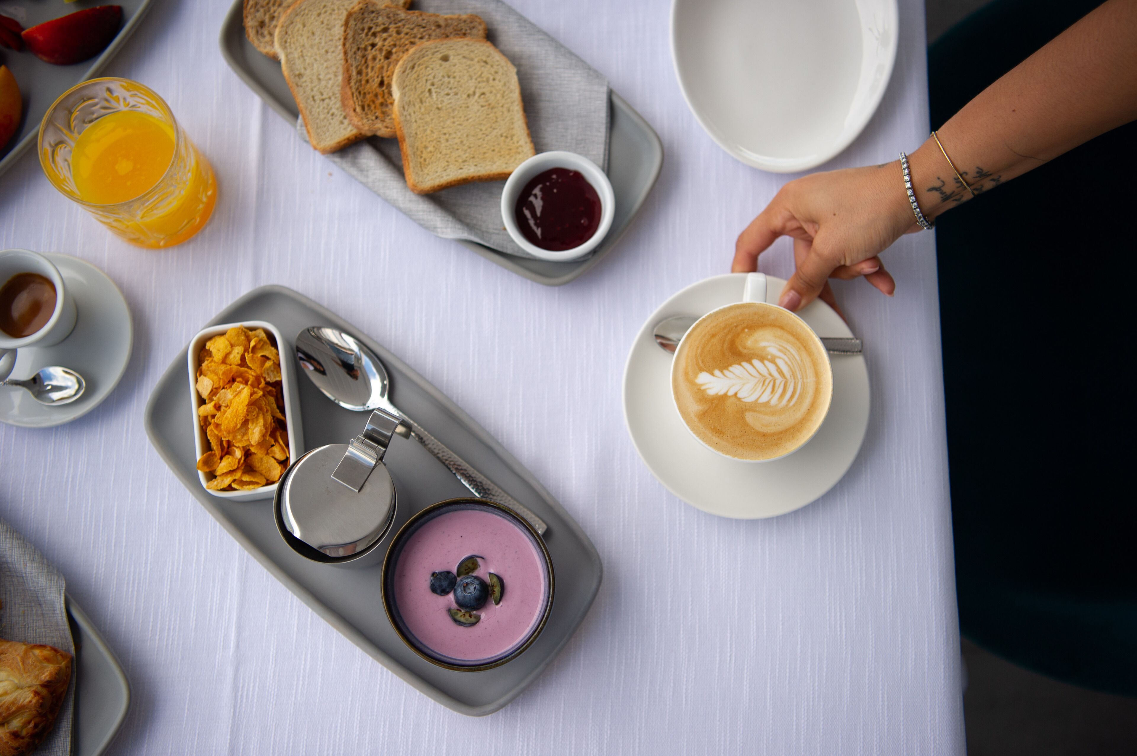 Un plateau de petit-déjeuner avec des toasts, des céréales, un smoothie et une tasse de café.