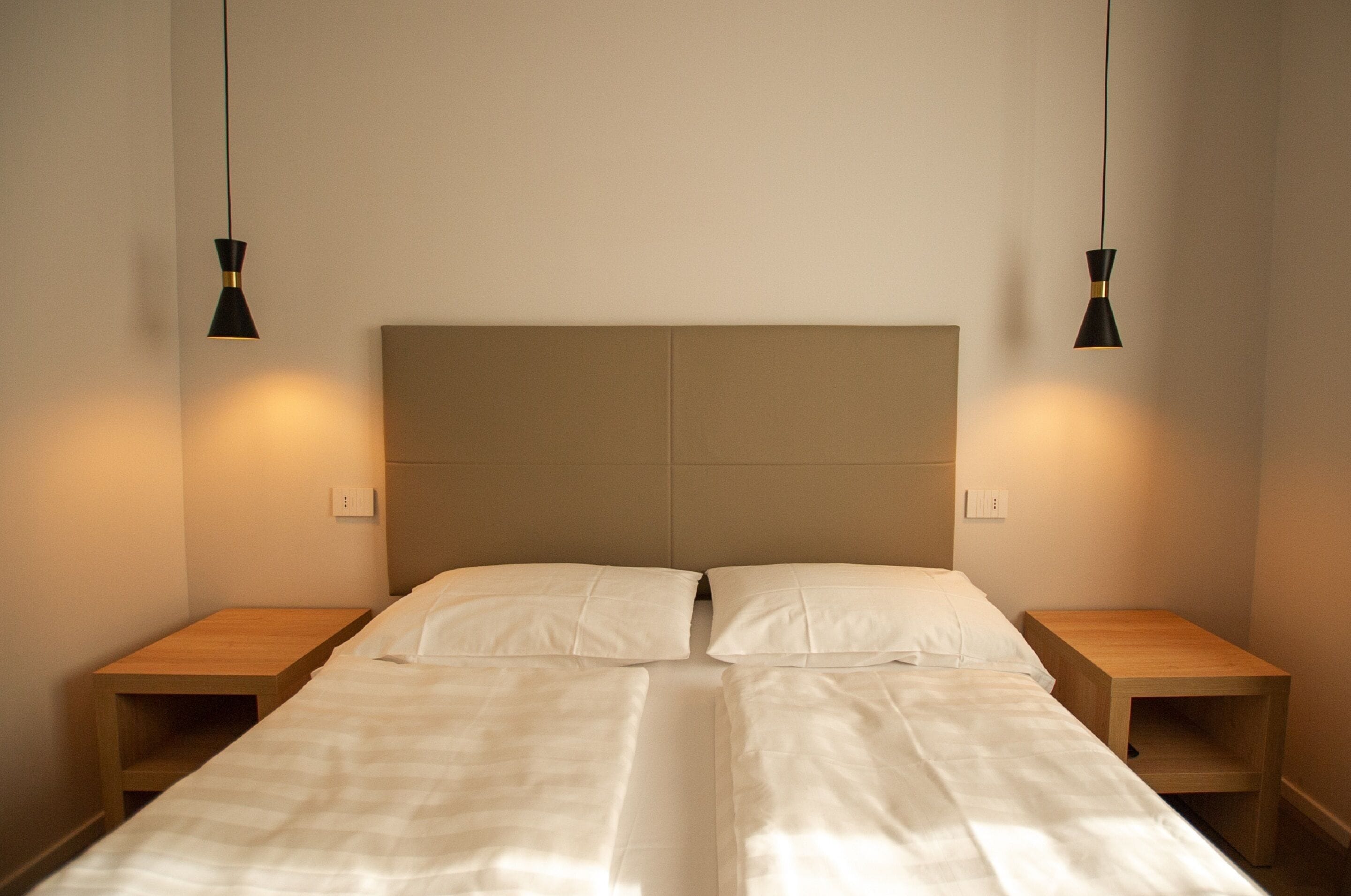 Een tweepersoonsbed met twee nachtkastjes, elk voorzien van een lamp.