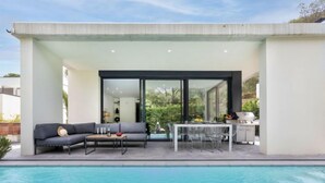 A modern outdoor pool area with a built-in seating area, a dining table, and a barbecue grill. - Vacation home Alyssa by Interhome (St Feliu de Guíxols)