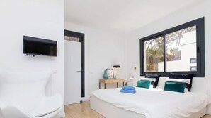 A modern bedroom with a bed, a TV mounted on the wall, a chair, and a window with a view. - Vacation home Alyssa by Interhome (St Feliu de Guíxols)