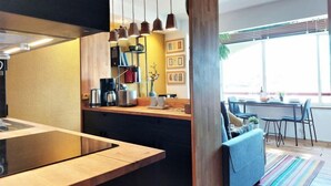 Eine moderne Küche mit Holzausziehtisch, hängenden Pendelleuchten und einem eingebauten Backofen.