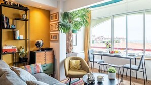 Ein modernes Wohnzimmer mit einer Couch, einem Couchtisch, einem Bücherregal und einem Essbereich mit Stühlen und einem Tisch.