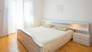 Un dormitorio con una cama, una mesita de noche y una ventana con cortinas.