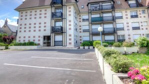 Un edificio de varios pisos con fachada simétrica, balcones y un estacionamiento al frente.