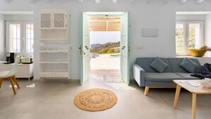 A bright, open-plan living area with a sofa, a coffee table, and a dining table. A large window provides a view of the outdoors. - Las Vistas by Interhome (Torrox Costa)
