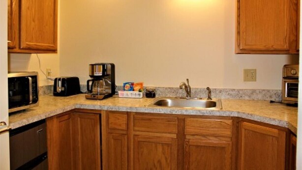 A compact kitchen with wooden cabinets, a built-in microwave, a coffee maker, and a sink. - 525 Sprague 6 · Apartment just outside of downtown Kalamazoo (Kalamazoo)