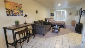 A compact living space with a bed, a sofa, a desk with a chair, and a TV. - 525 Sprague 6 · Apartment just outside of downtown Kalamazoo (Kalamazoo)