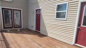 A house with a wooden deck, a red door, and a window. - 525 Sprague 6 · Apartment just outside of downtown Kalamazoo (Kalamazoo)