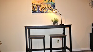 A dark wooden console table with two lower shelves, a floor lamp, and a painting of sunflowers on the wall. - 525 Sprague 6 · Apartment just outside of downtown Kalamazoo (Kalamazoo)