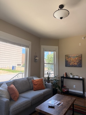 A living room with a grey sofa, a coffee table, a painting, and a ceiling light fixture.