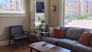 Una sala de estar con sofá, sillón, mesa de centro y una planta.