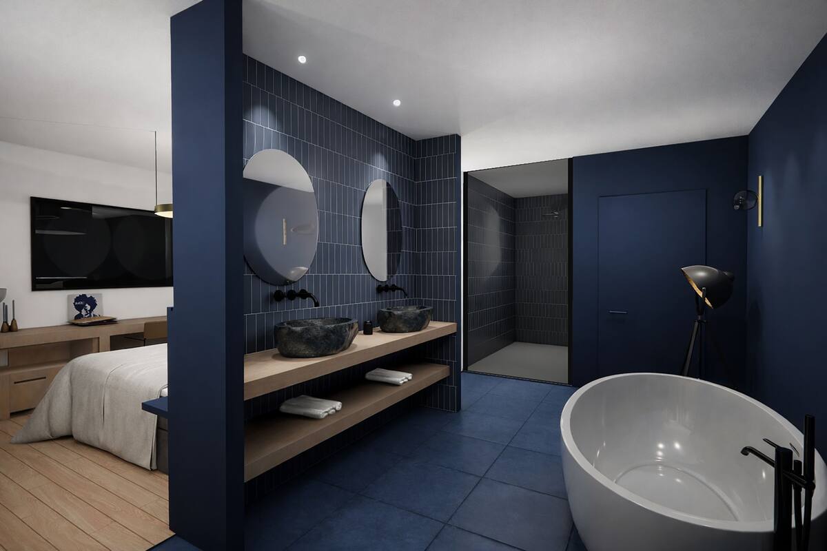 A modern bathroom with dark blue tiles, a large freestanding bathtub, and a vanity with two mirrors and a sink.