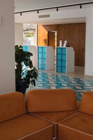 A modern lobby with a geometric patterned floor, a reception desk with blue accents, and orange seating.