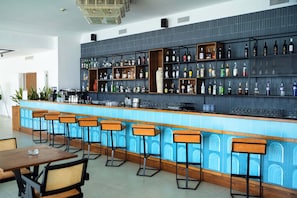 A bar area with a blue tiled counter, wooden stools, and shelves stocked with various bottles. - Admiral Hotel (Sorrento)