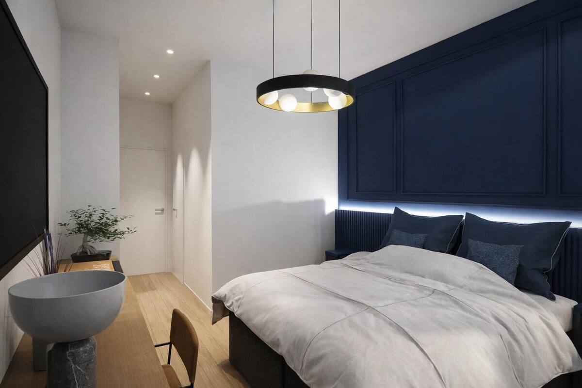 A modern bedroom with a large bed, a bedside table, a floor lamp, and a potted plant.