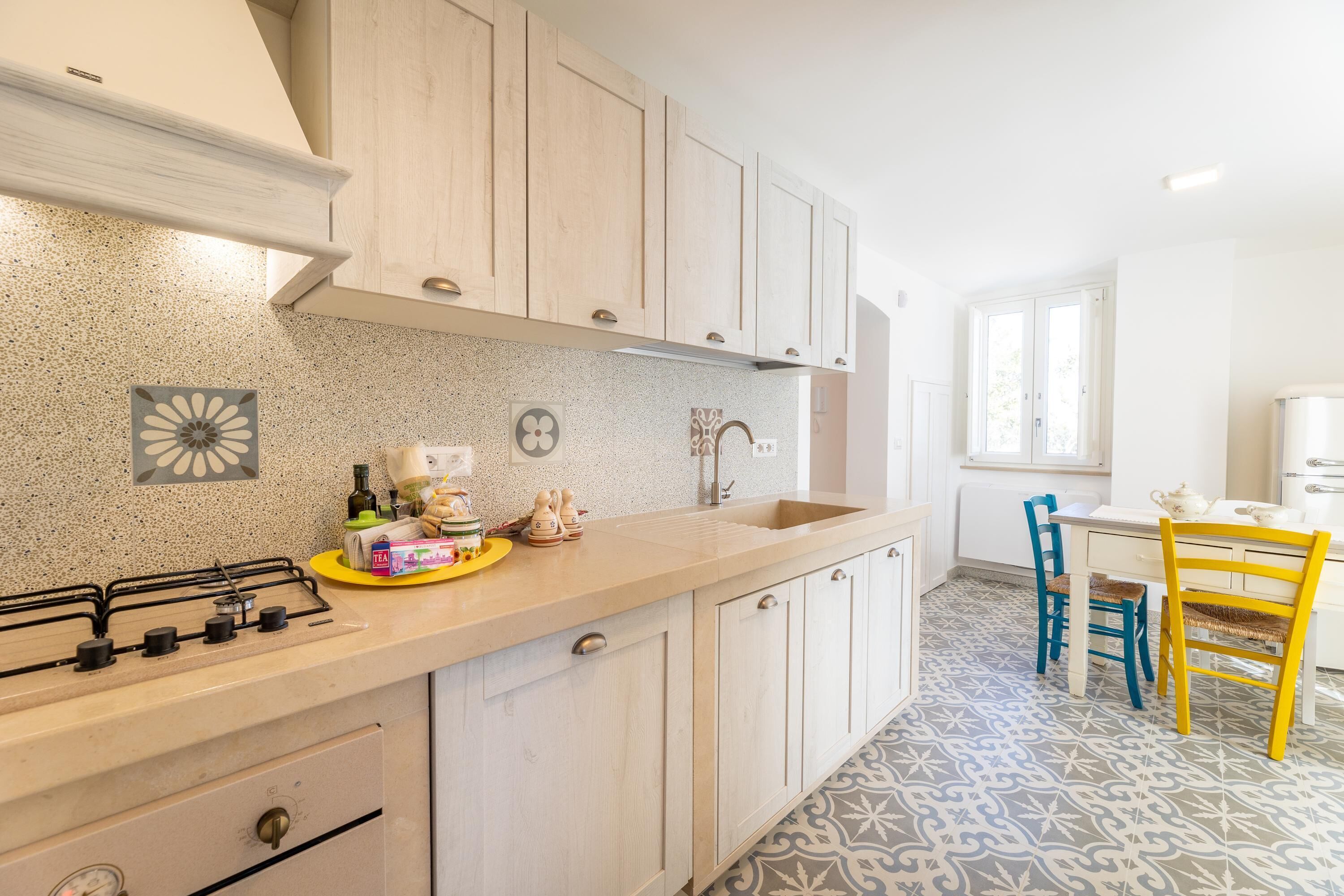 A kitchen with a gas stove, wooden cabinets, a sink, and a dining area with a table and chairs.