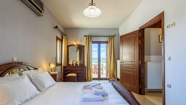 A bedroom with a bed, a dresser, a mirror, and a view of the outdoors.
